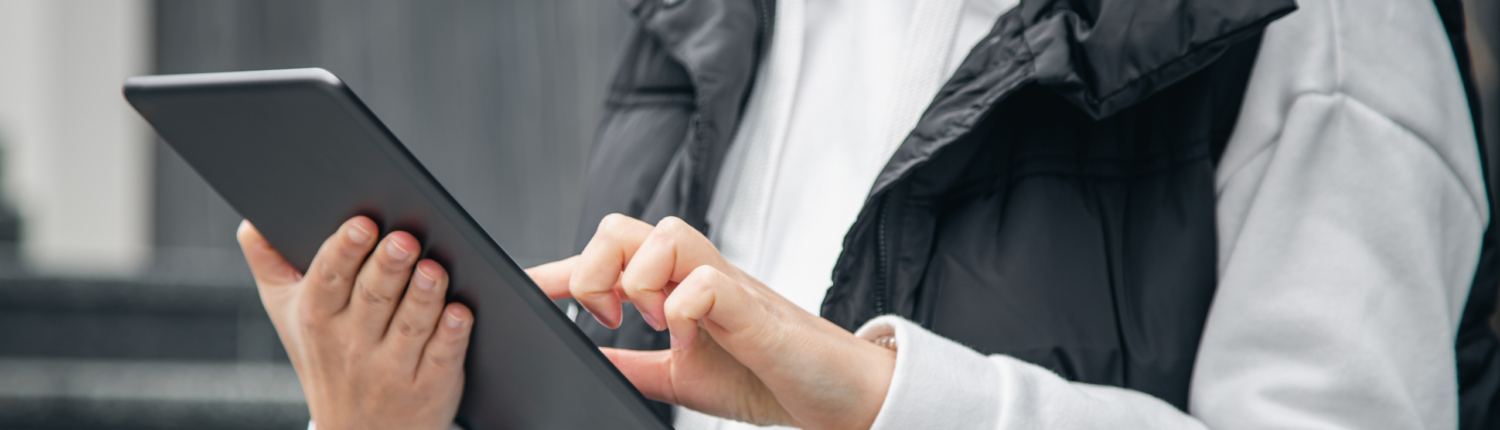 Close-up, a woman is using a tablet on a blurred city background.